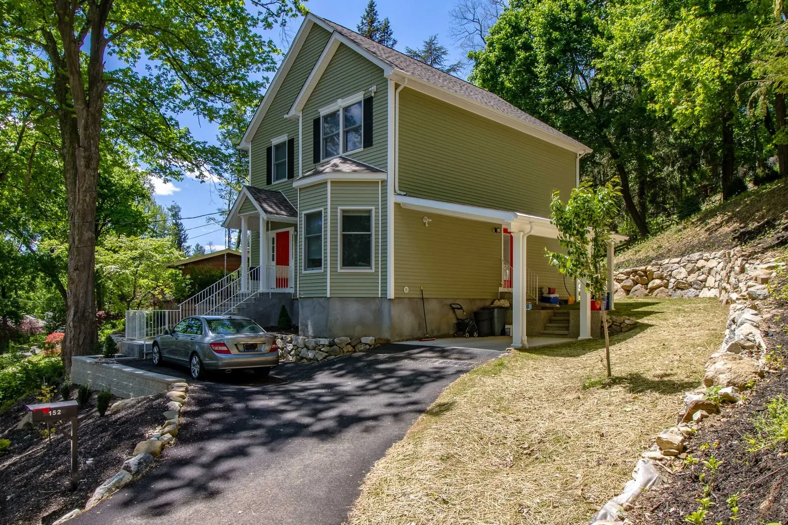 Green two-story home with a covered side porch