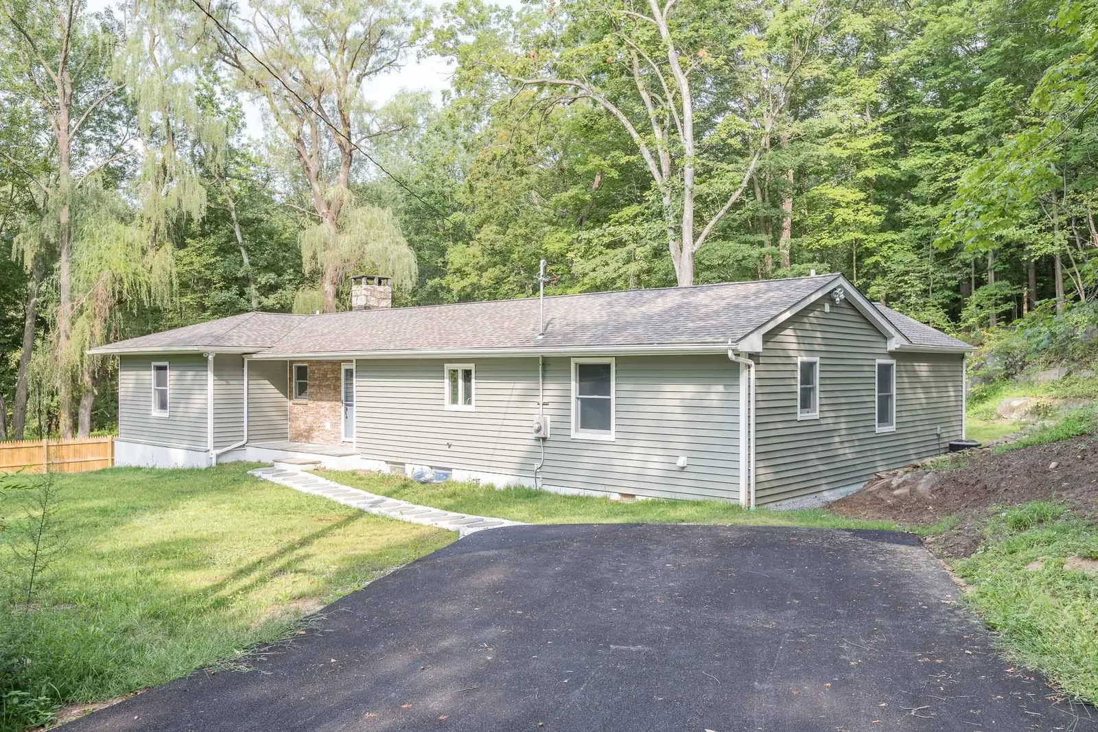 Long green ranch set into the wooded lot