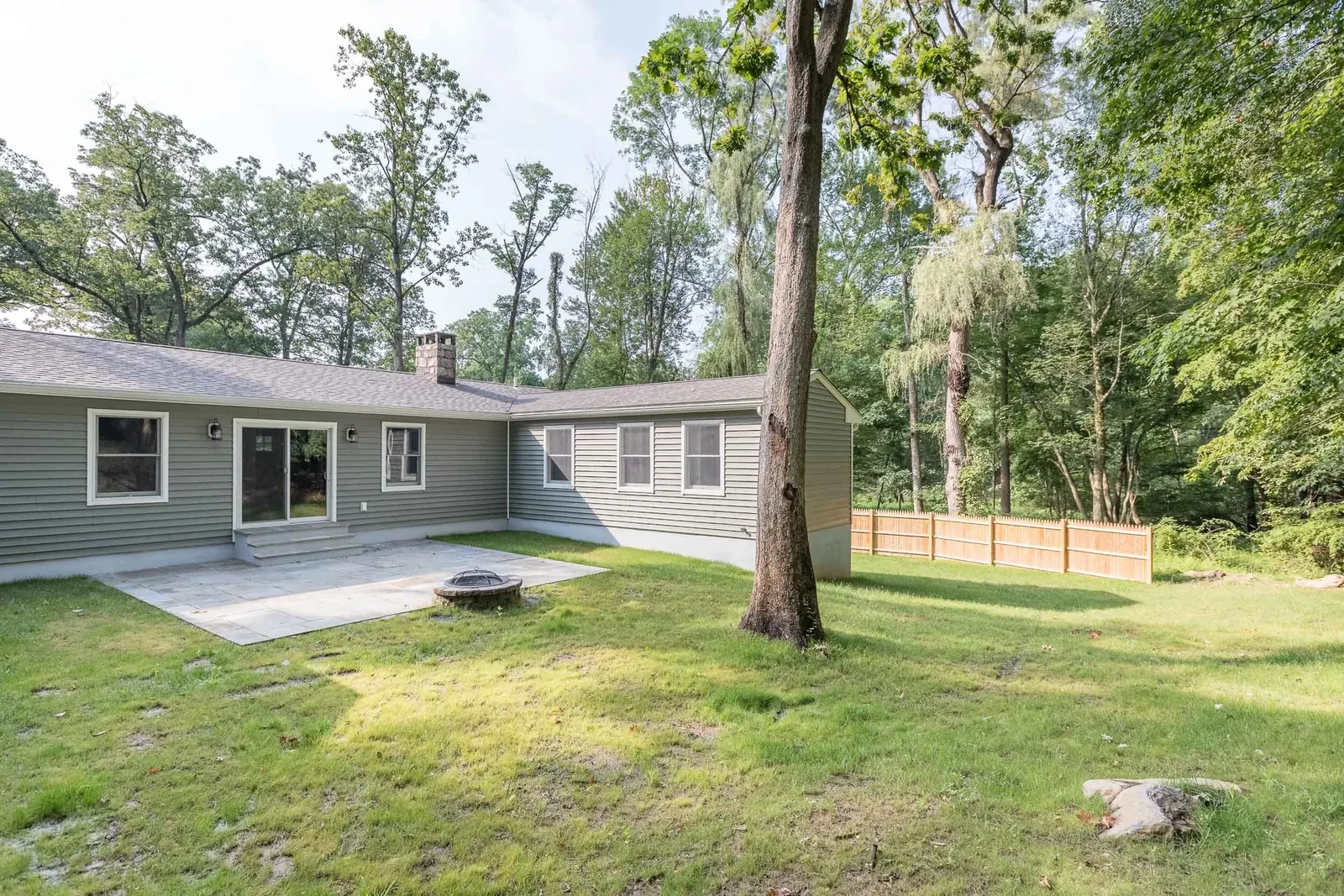 Green ranch and detached structure through the trees