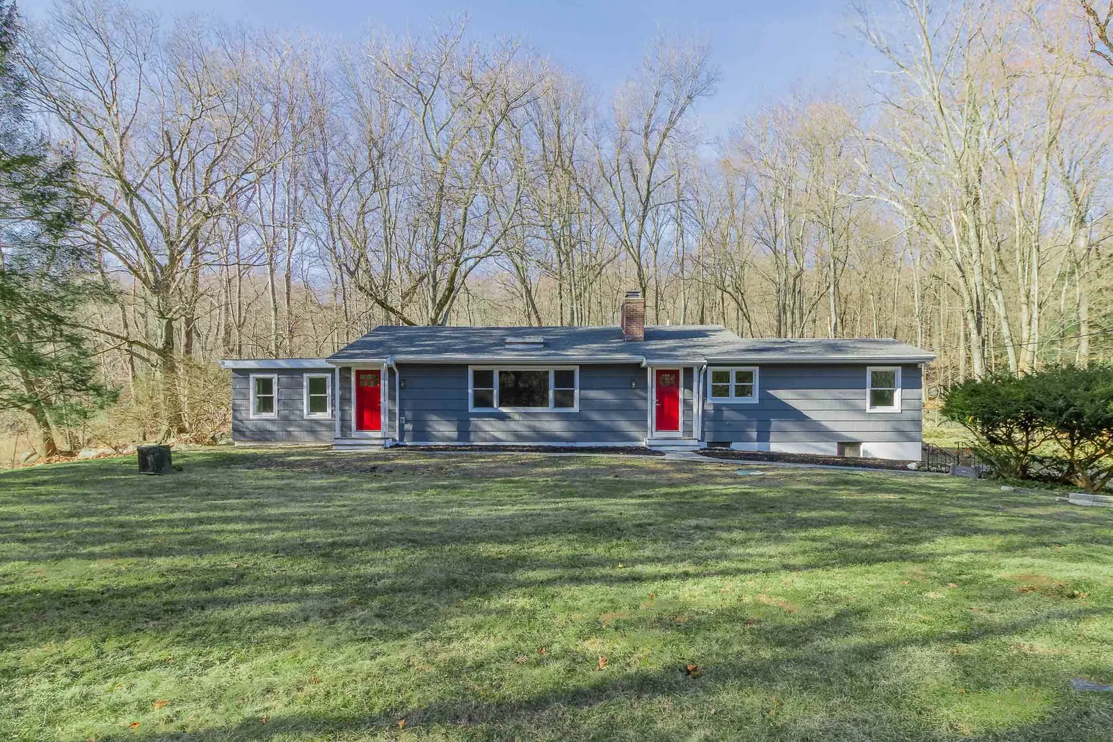Gray raised ranch with red doors in winter