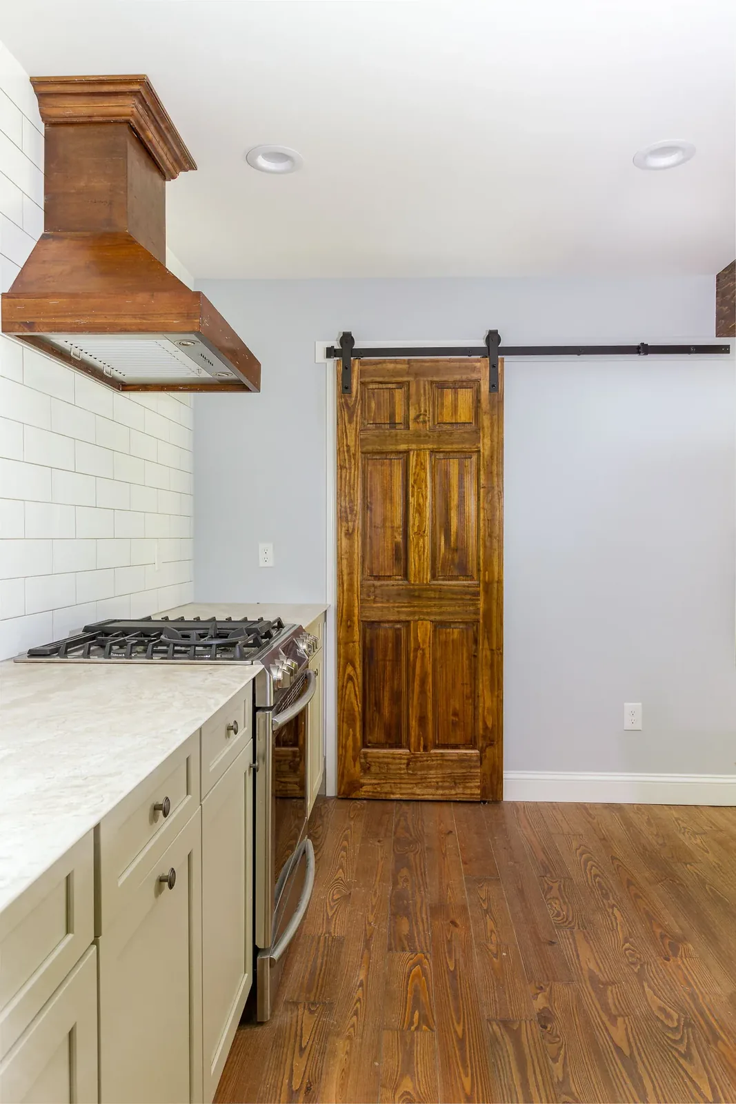 Kitchen with wood range hood and sliding barn door