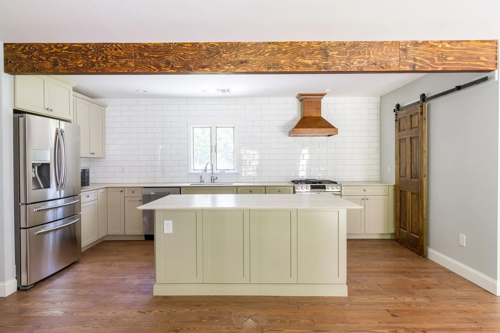 White kitchen with wood beam and green island