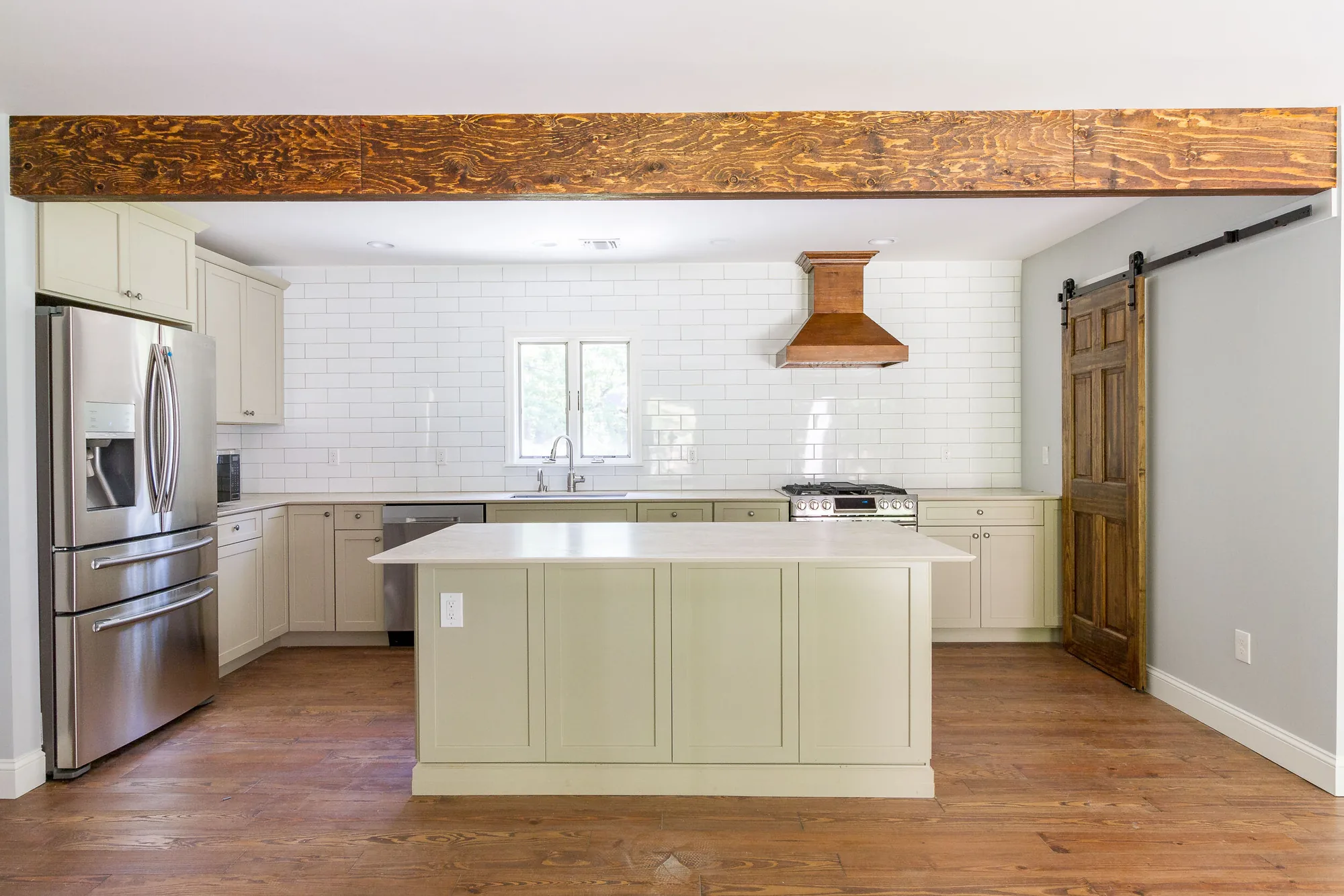 Sage kitchen with reclaimed wood beam and subway tile
