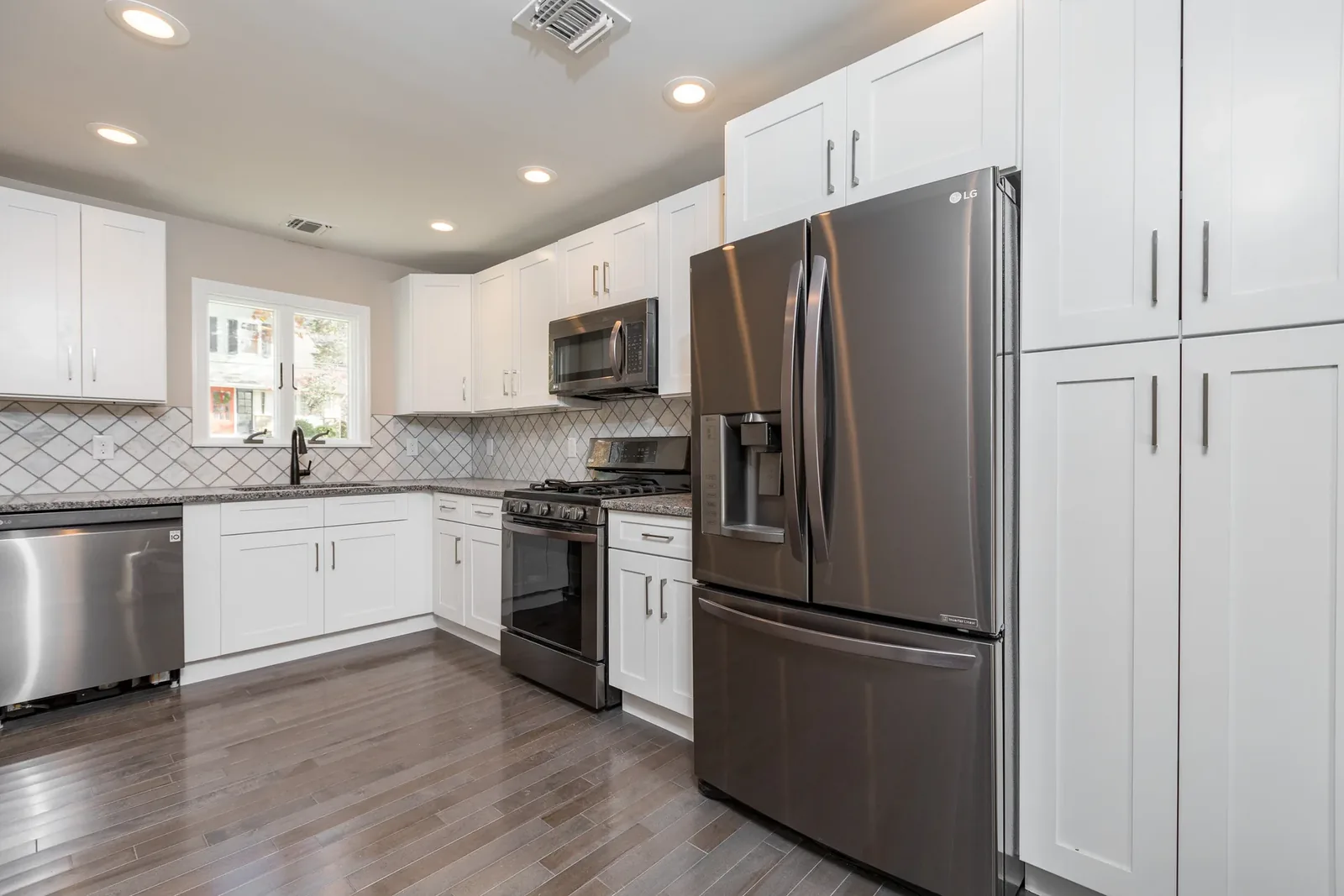 White kitchen with arabesque tile and black-stainless appliances
