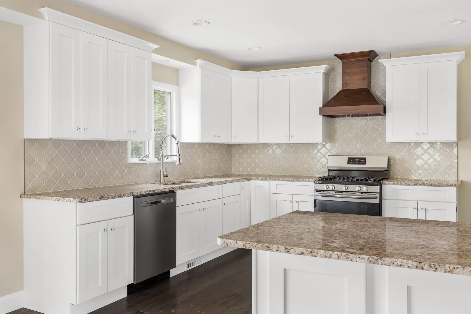 White kitchen with arabesque tile and wood range hood