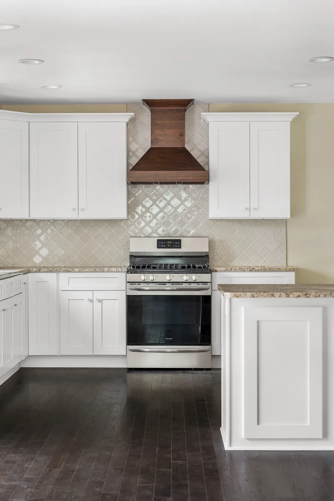 Gas range under a wood range hood and arabesque tile