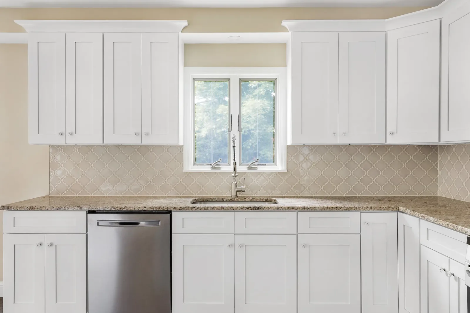 White kitchen with granite counters and wood range hood