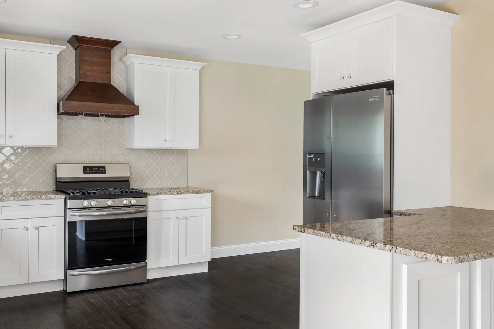 White kitchen with granite island and stainless refrigerator
