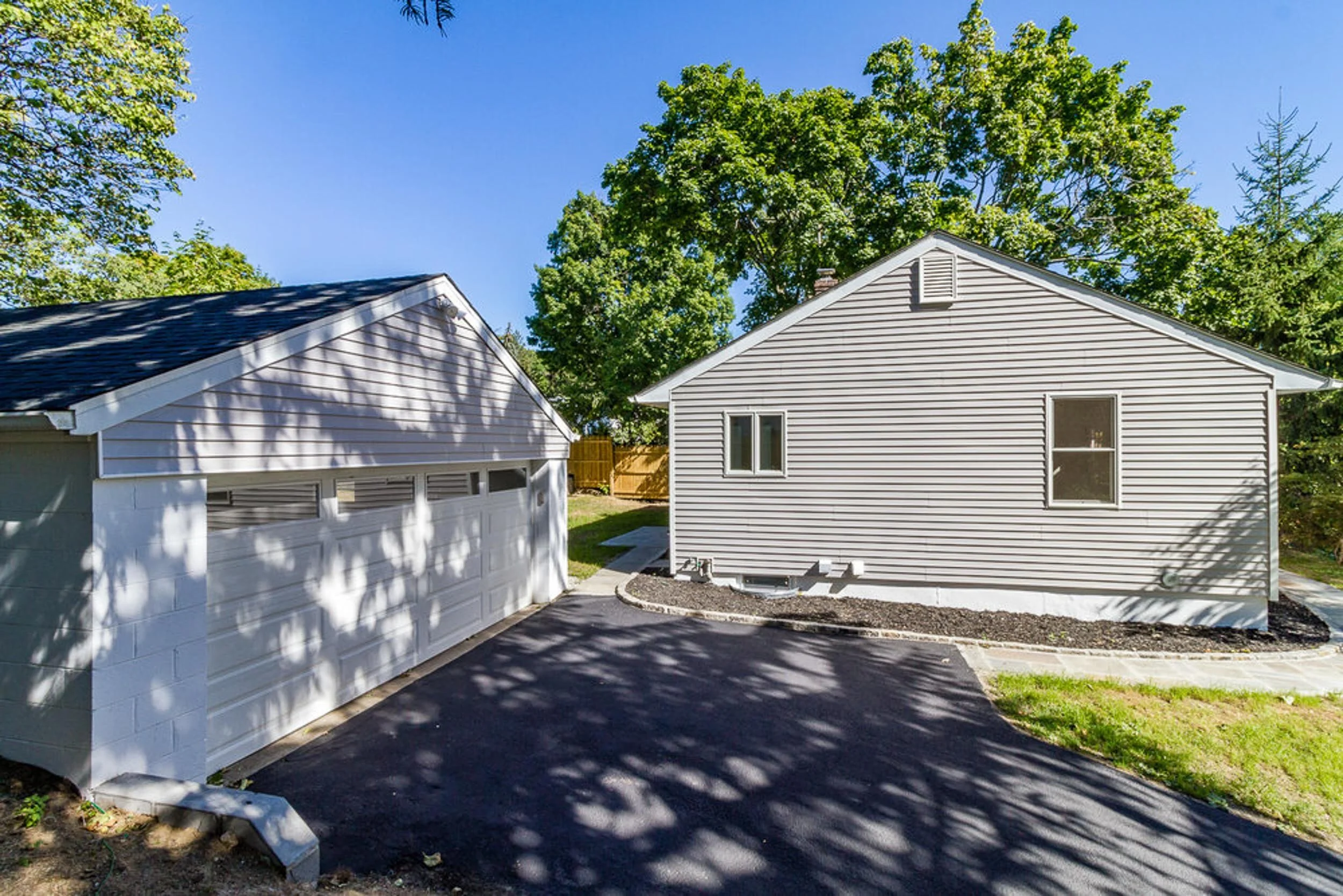 A detached two-car garage with siding that matches the main house, and a new driveway between them