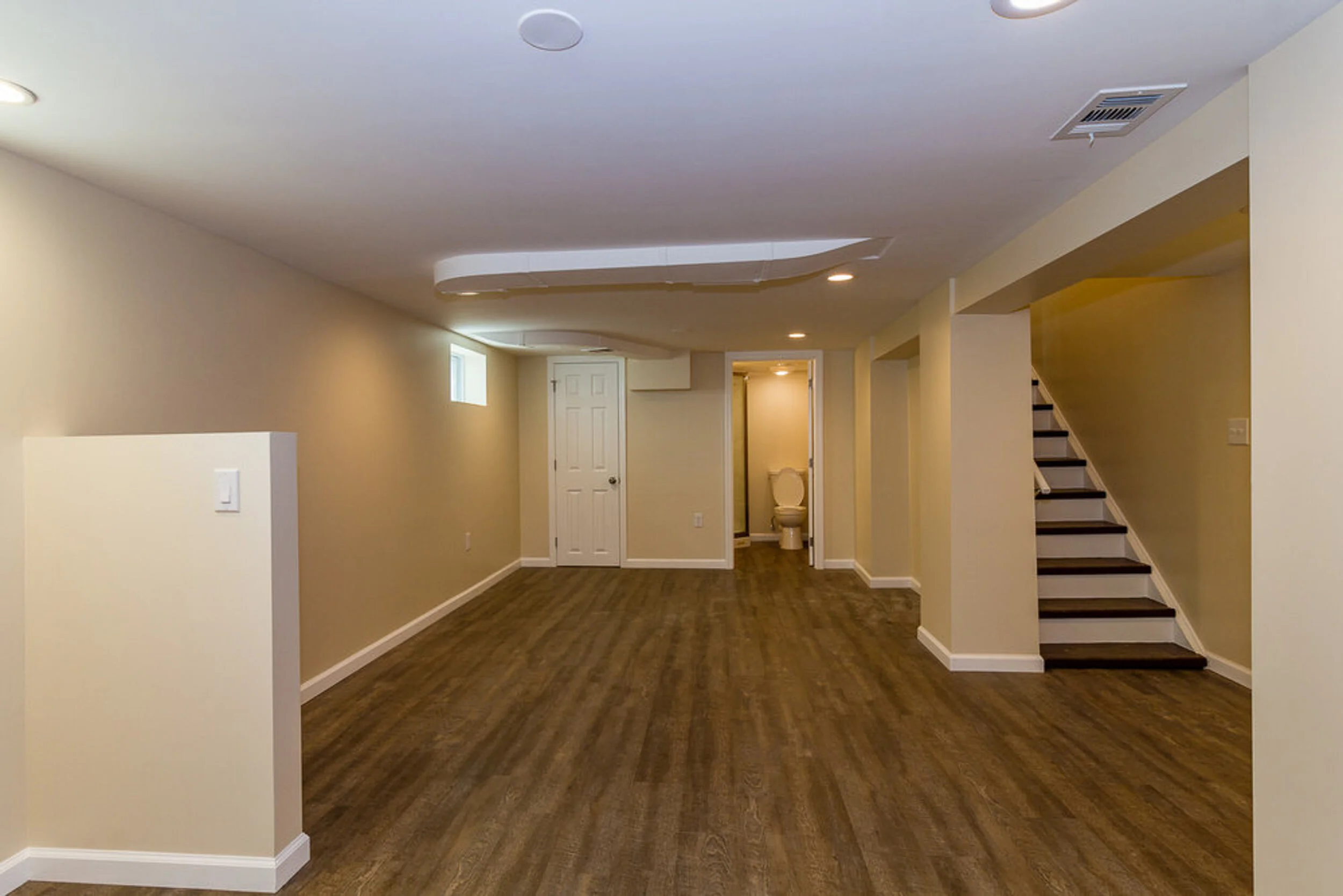 Finished basement with wood-look flooring, recessed lighting, and a staircase in a Croton-on-Hudson home