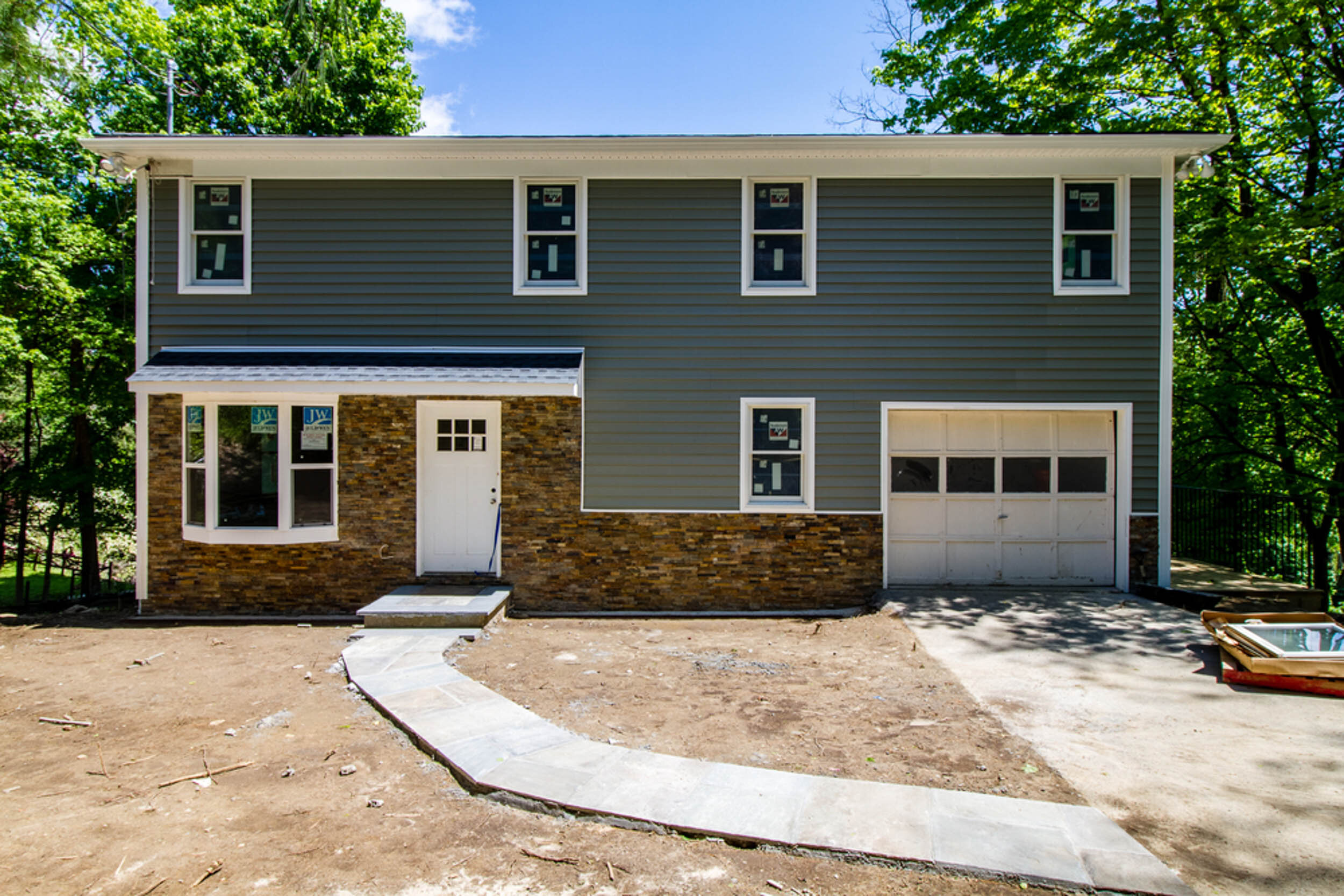 Newly built two-story home with gray siding, stone veneer, and an attached garage