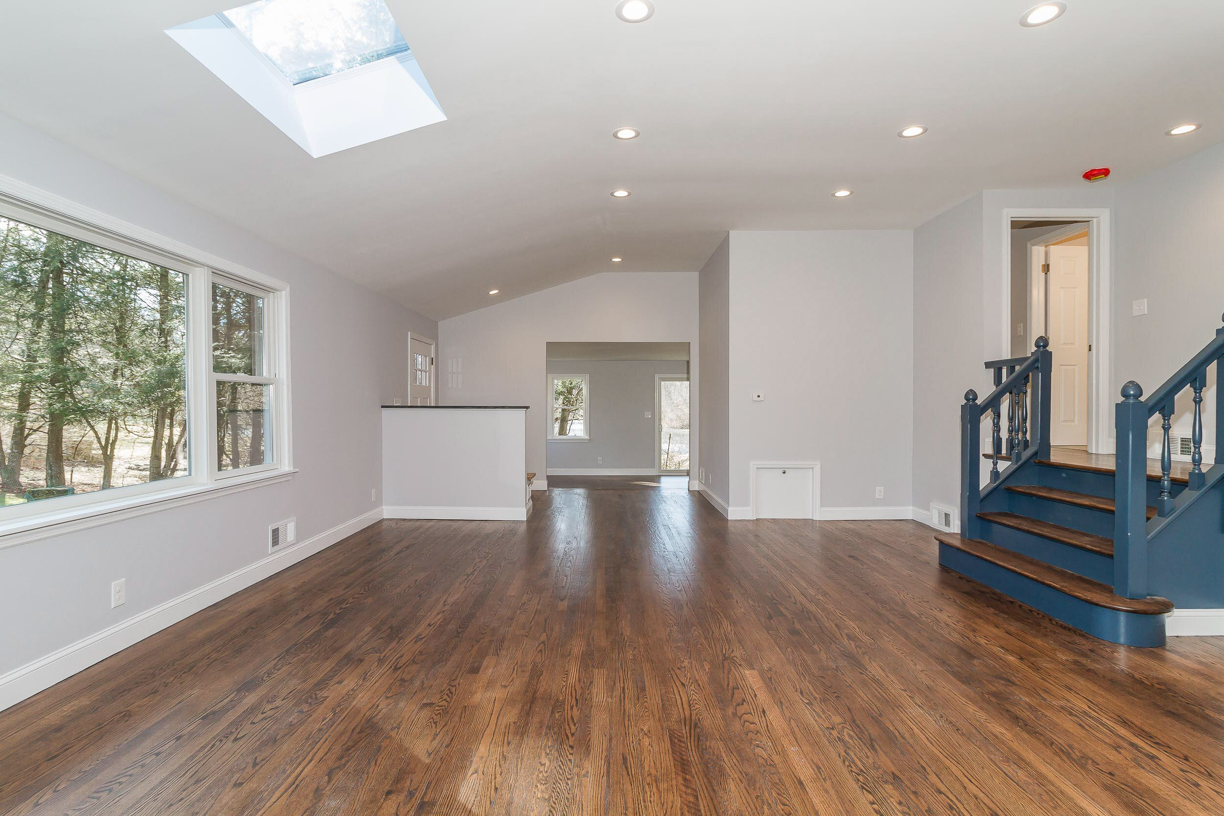 Open living room with skylight and blue staircase