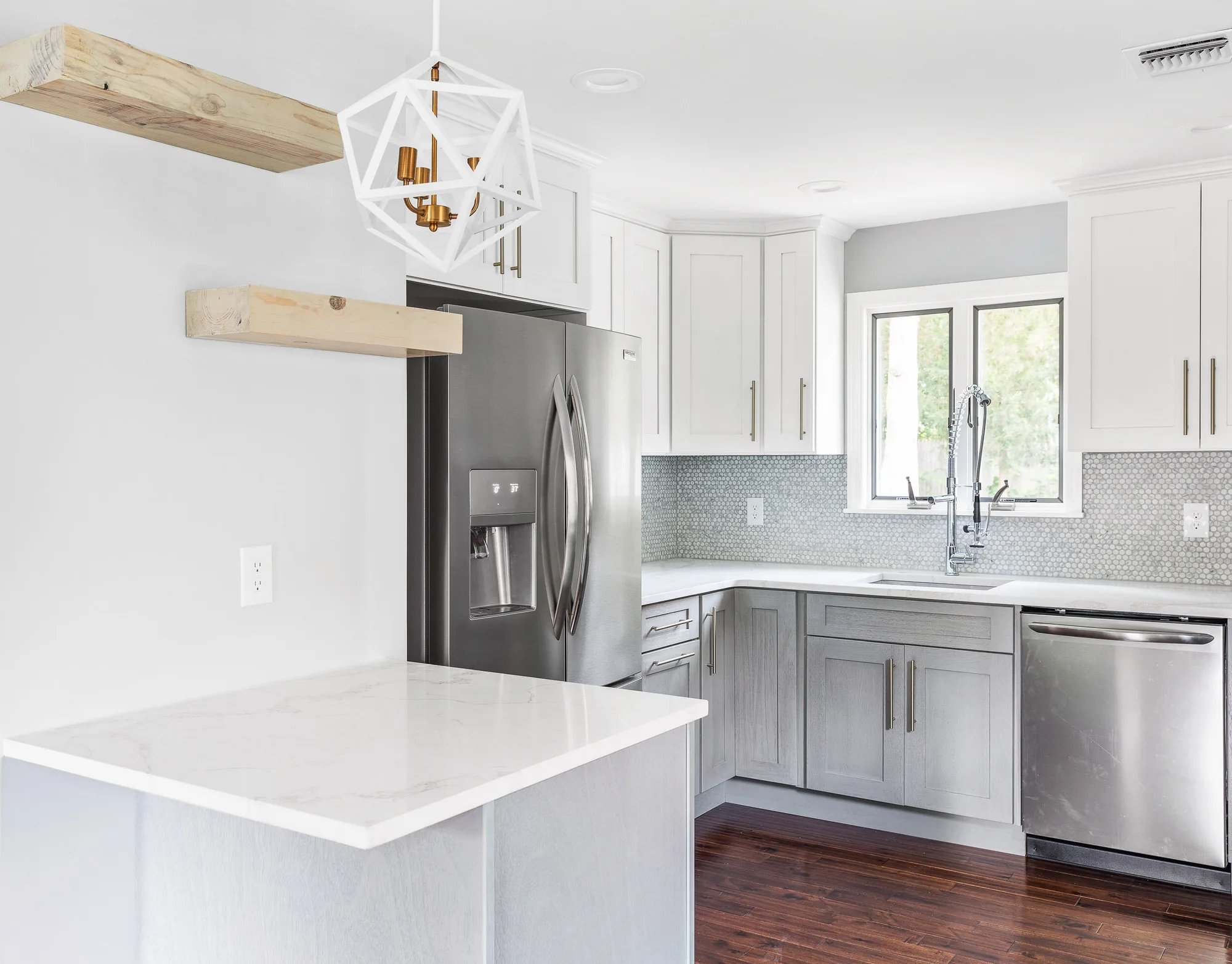 Two-tone kitchen with white upper cabinets, gray lower cabinets, a marble waterfall island, and floating wood shelves