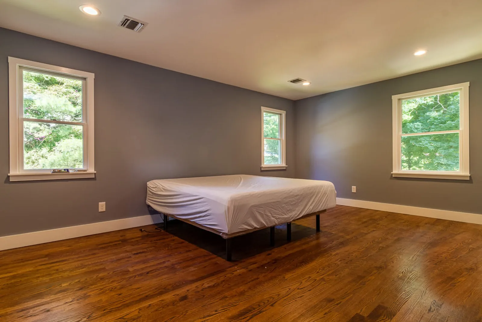Bedroom with mauve walls, a wood bed frame, and a large window