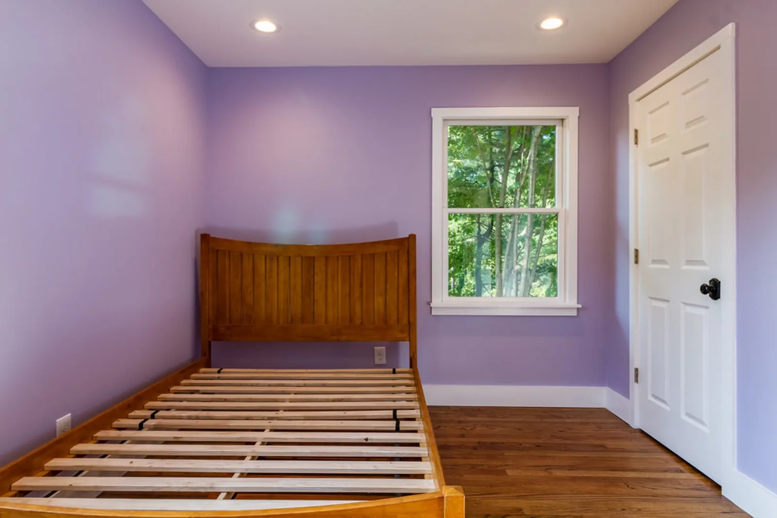 Bedroom with lavender walls and hardwood floors