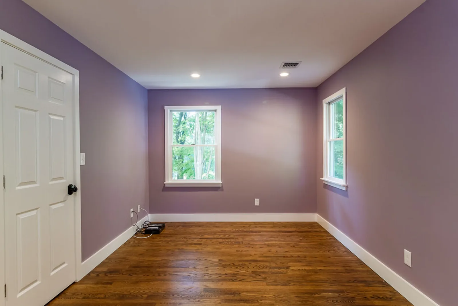Room with lavender walls, hardwood floors, and bright windows