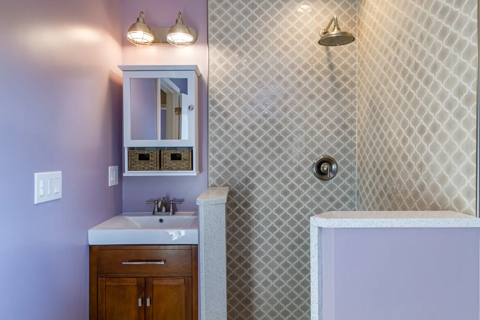 Master bath vanity with patterned walls, a framed mirror, and sconces