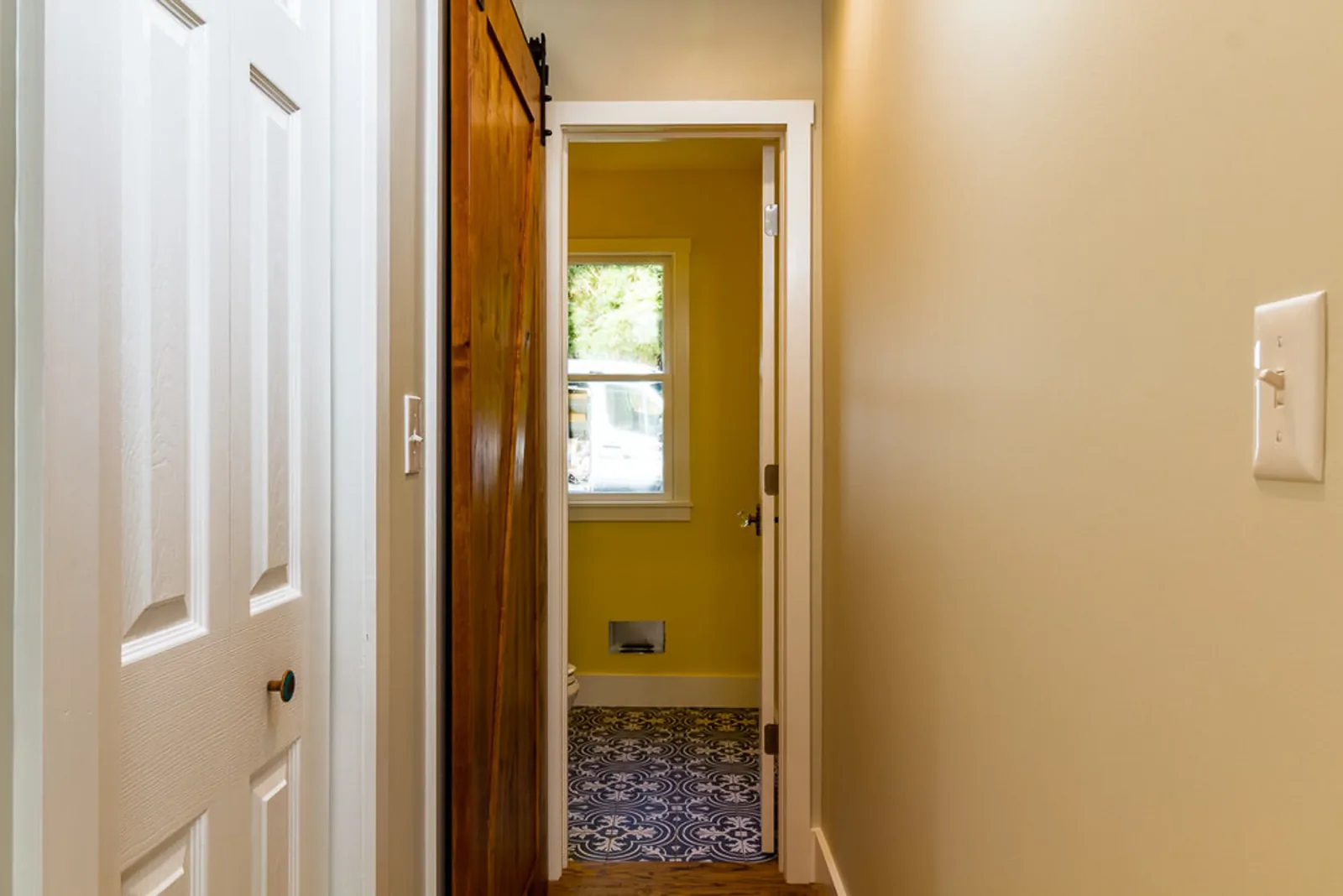 Hallway with white doors leading to a bath with patterned floor tile