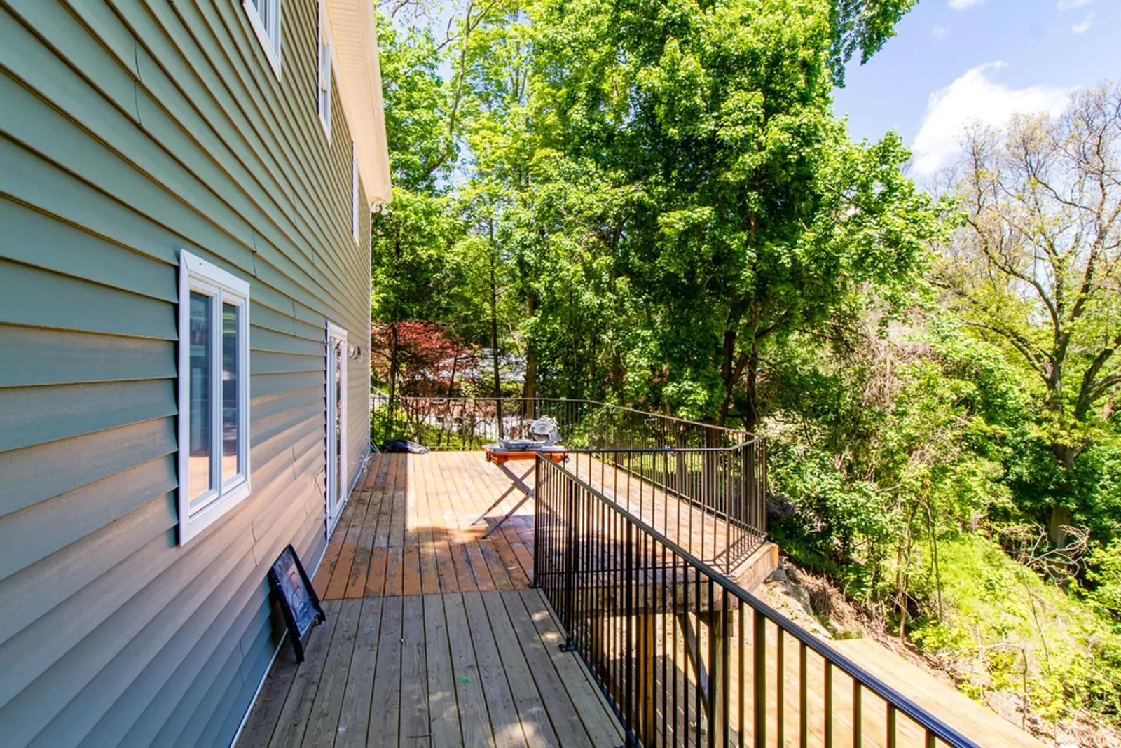 Elevated wood deck with a black railing off the back of the home