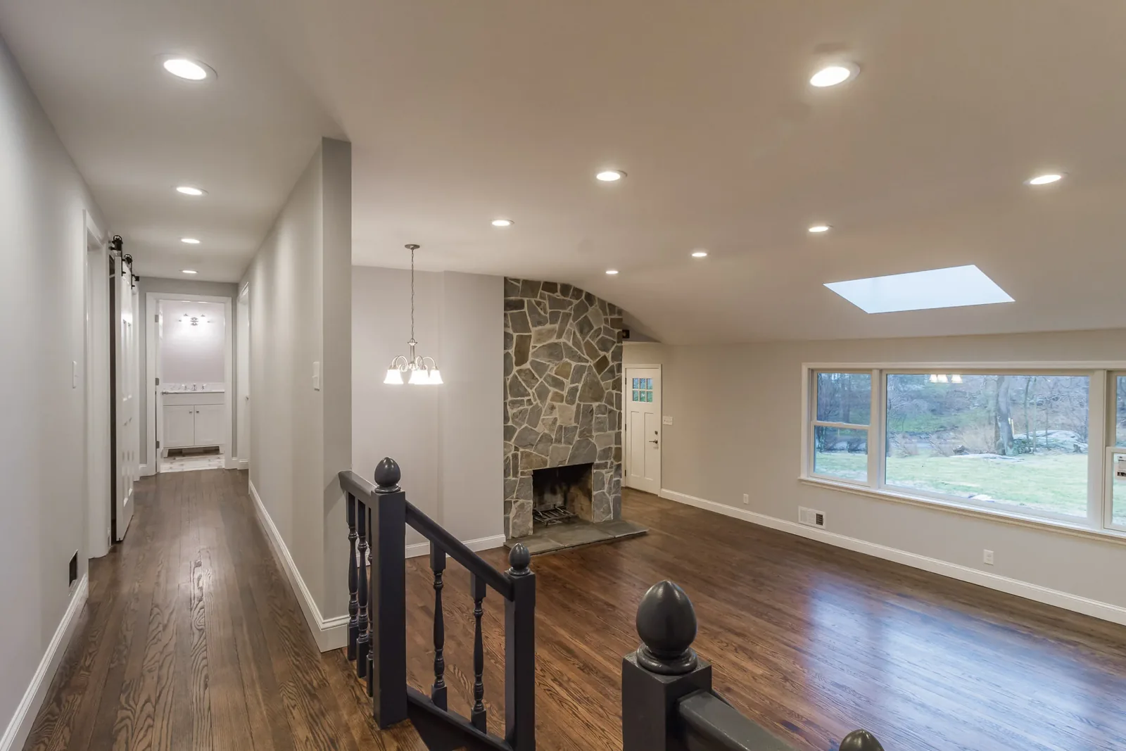 Sunken living room with a stone fireplace and hardwood floors