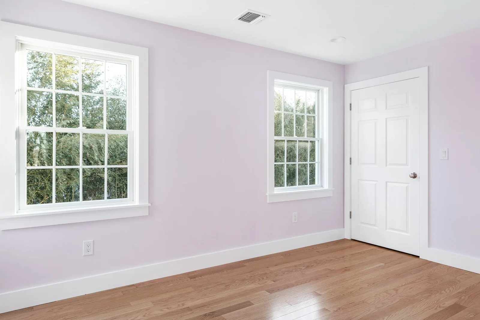 Bedroom with pale lavender walls and hardwood floors