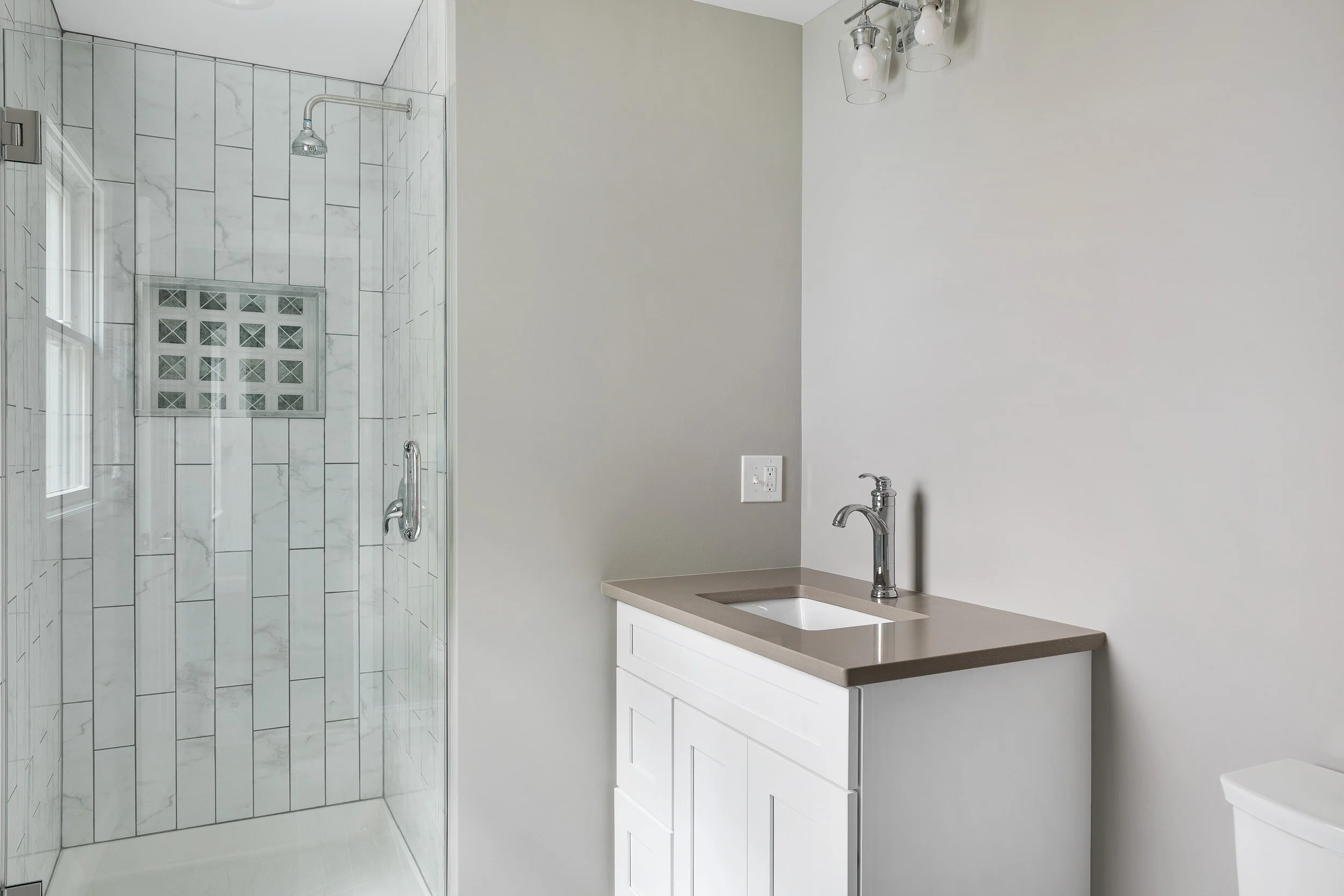 Bathroom with glass shower and quartz-top vanity
