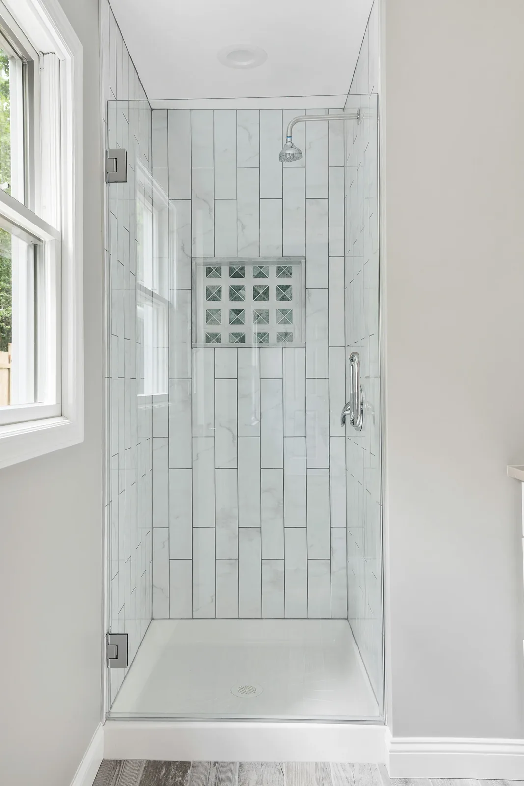 Tiled shower with mosaic niche and glass door