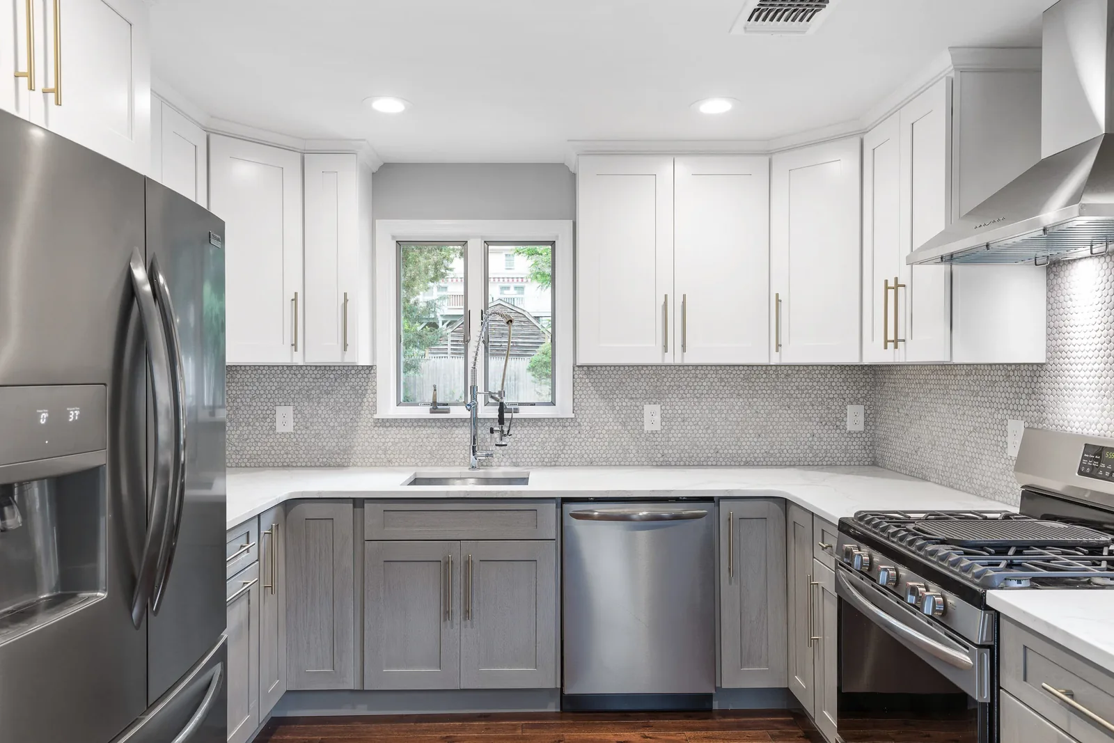 Two-tone kitchen with white uppers, gray lowers, and penny-round backsplash