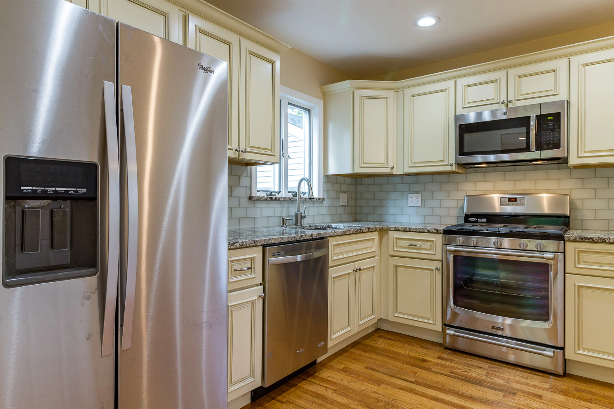 New kitchen with cream cabinets, granite counters, and stainless appliances