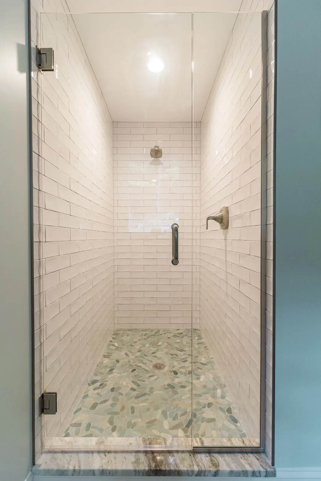 Glass shower with subway tile and pebble floor