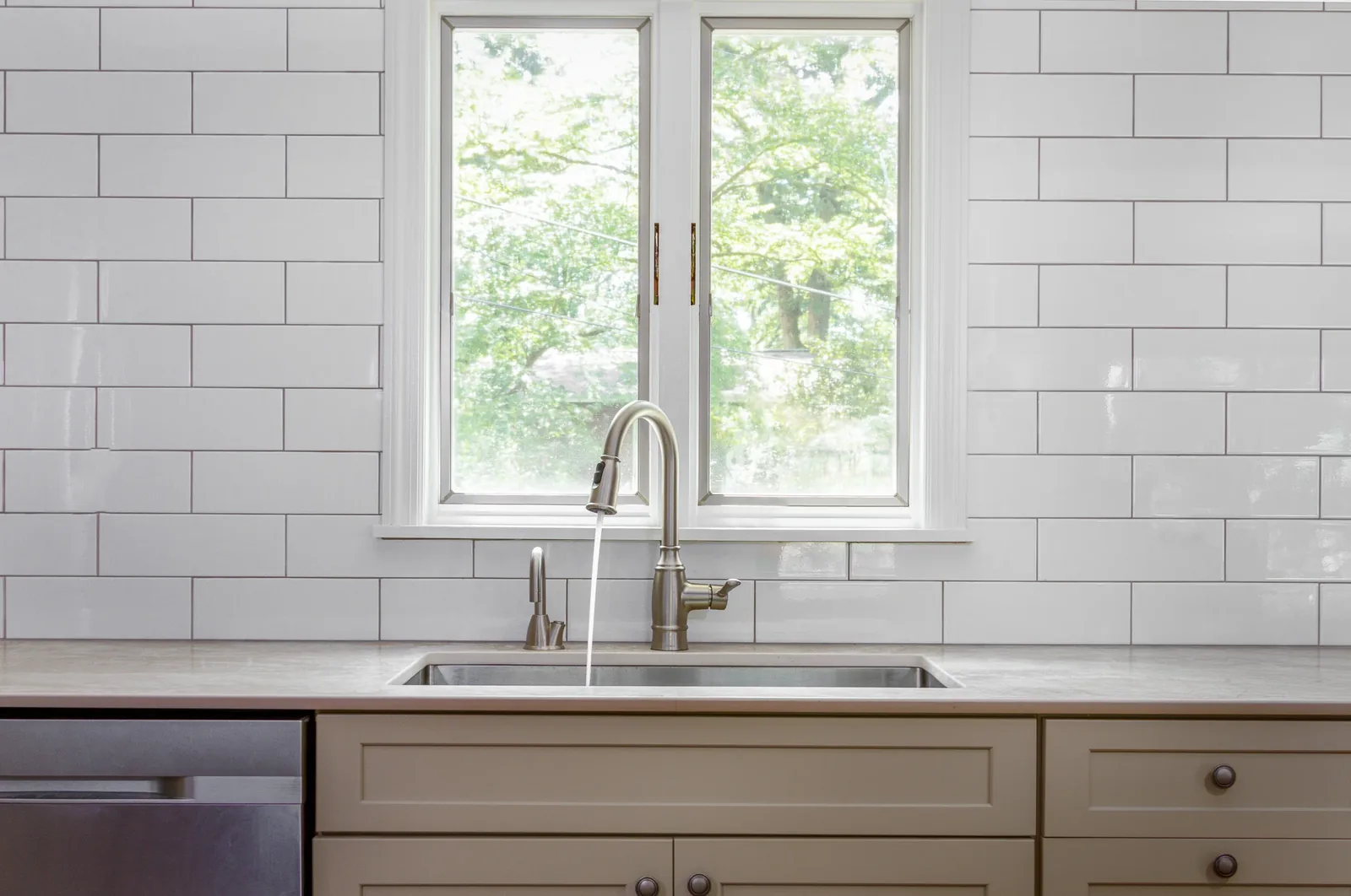 Sink wall with white subway tile and casement windows