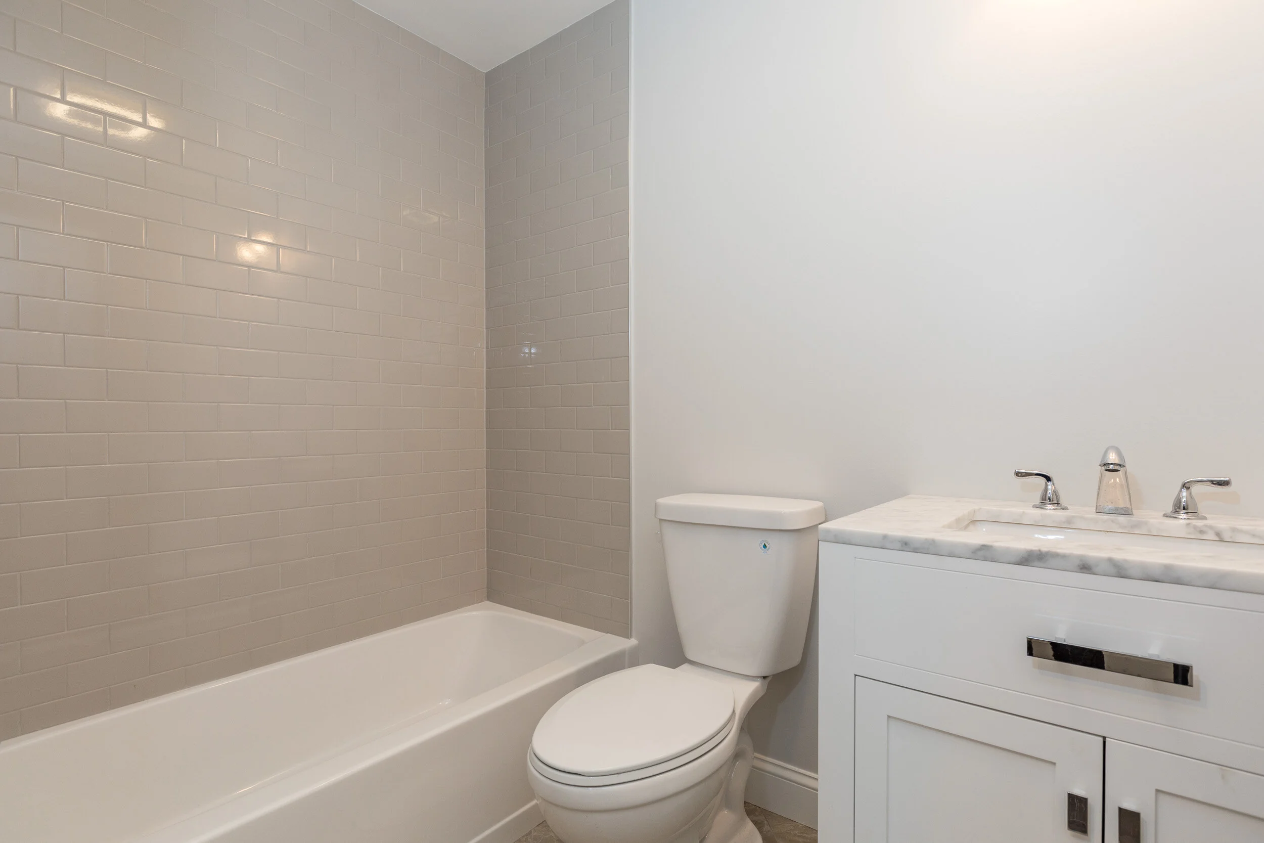 Bathroom with subway-tile tub surround and marble-top vanity
