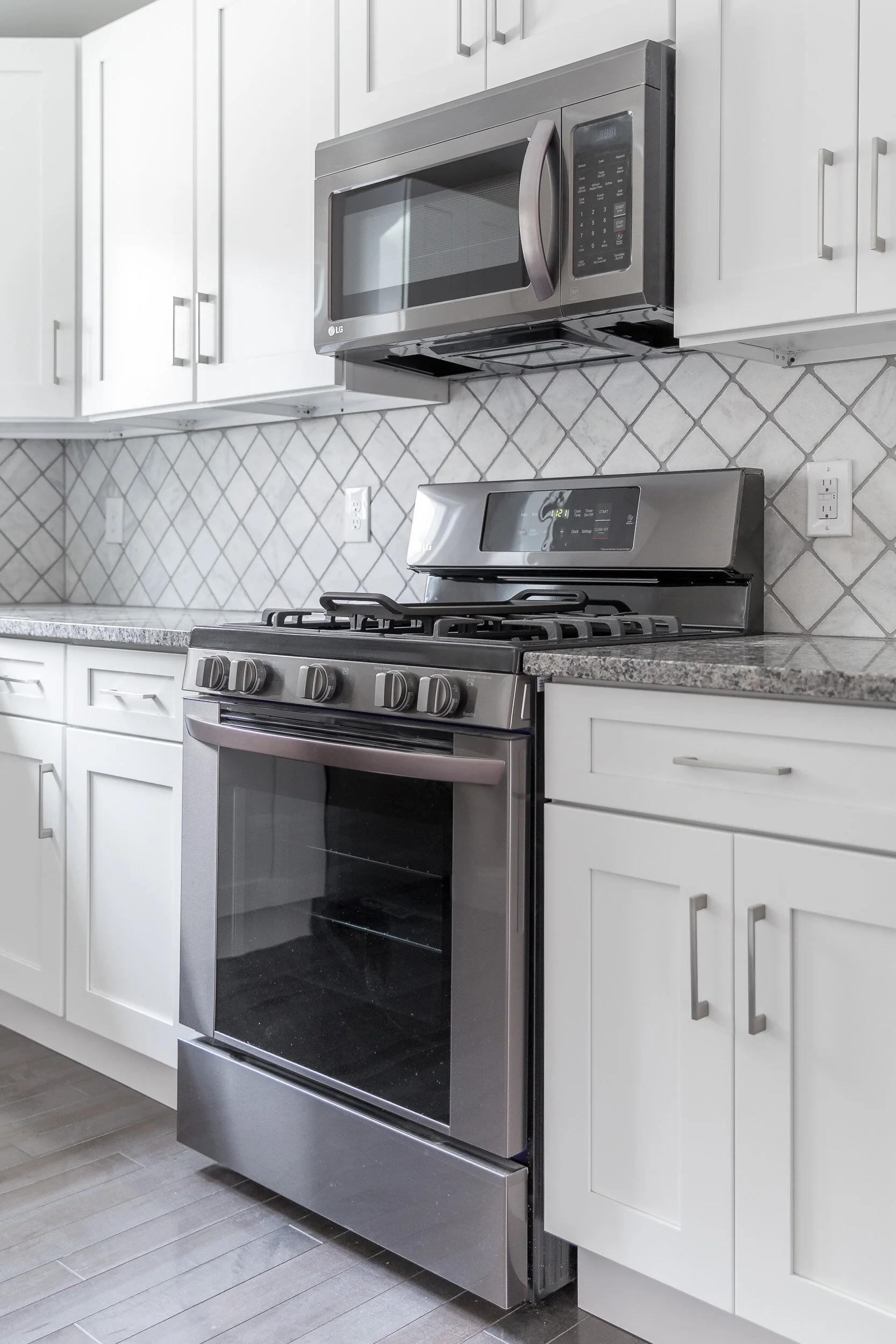 White shaker kitchen with gas range and black-stainless microwave