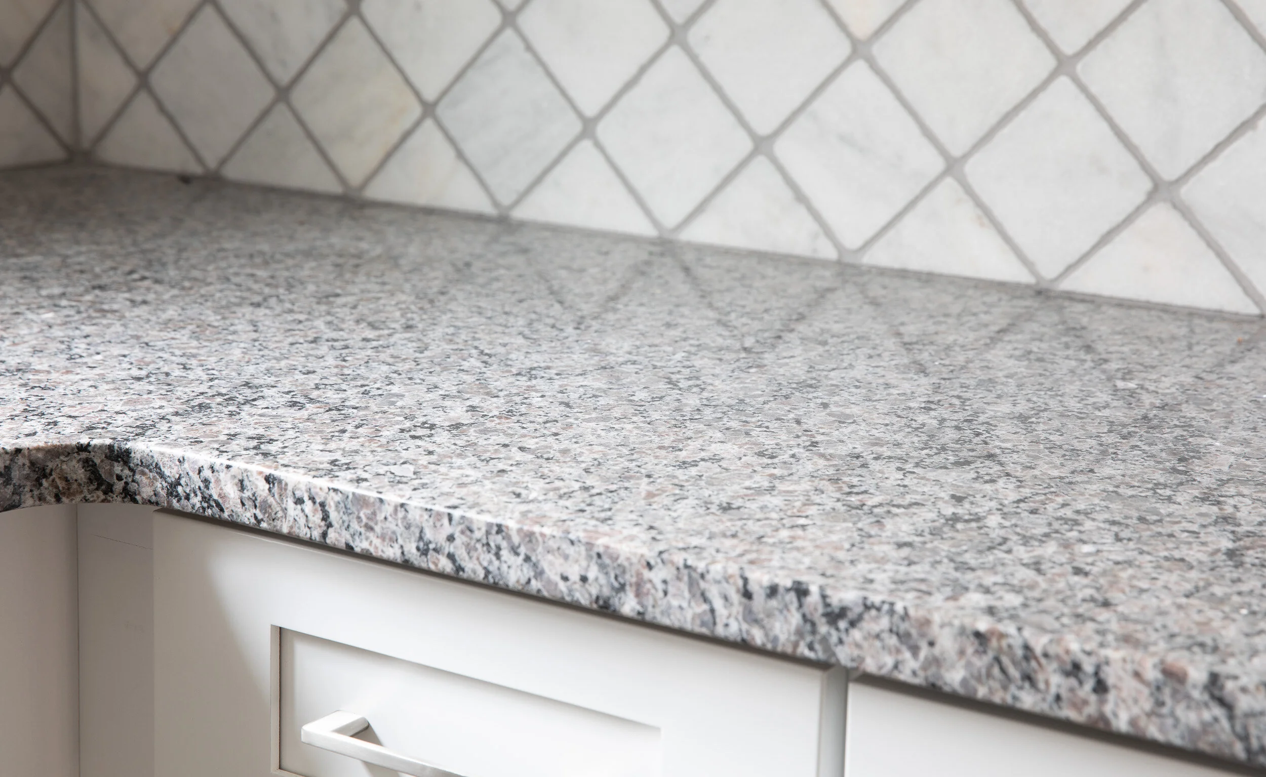Granite counter edge against the arabesque tile backsplash